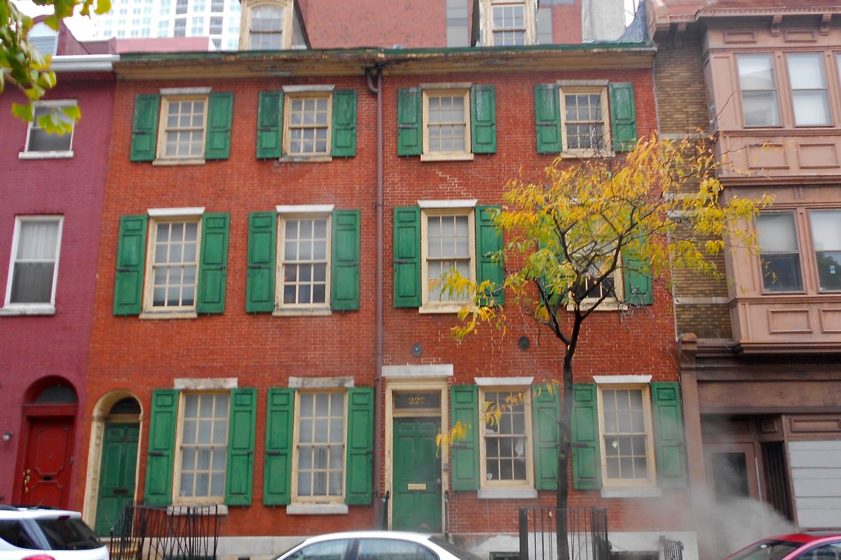 Red brick rowhouses with green shutters on 9th Street in the Bella Vista neighborhood of Philadelphia